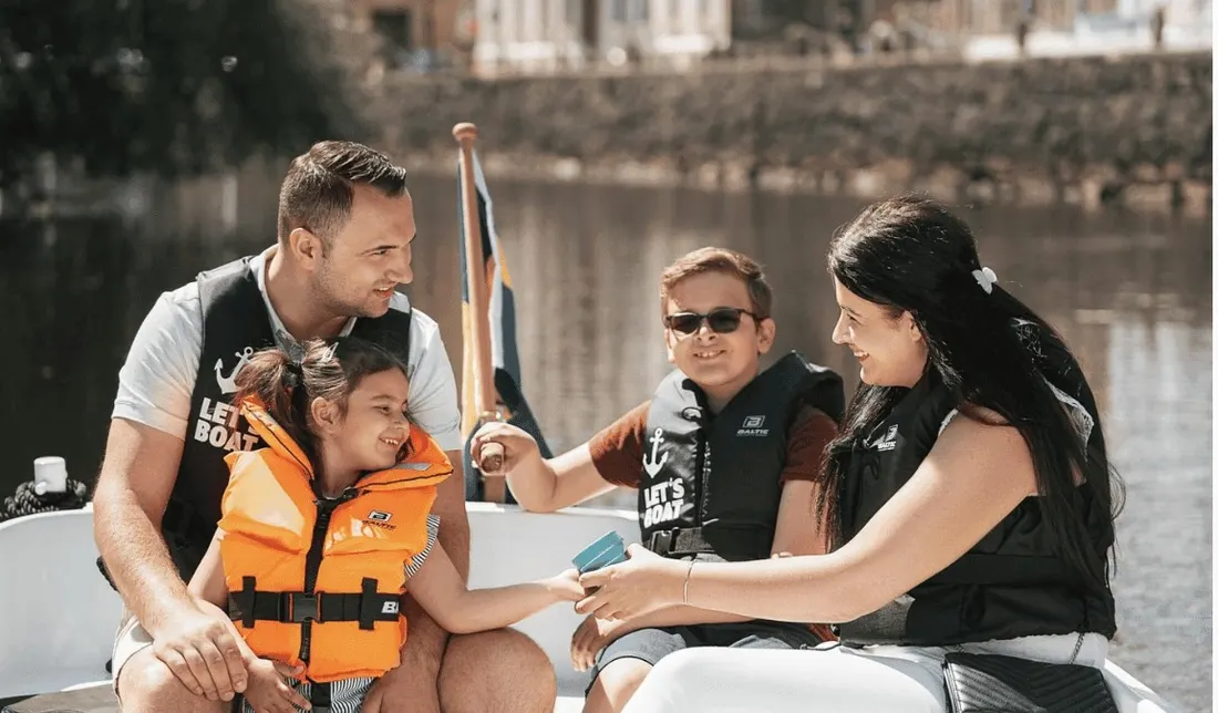Familj med barn i flytvästar ombord på en elbåt i Göteborgs kanal.