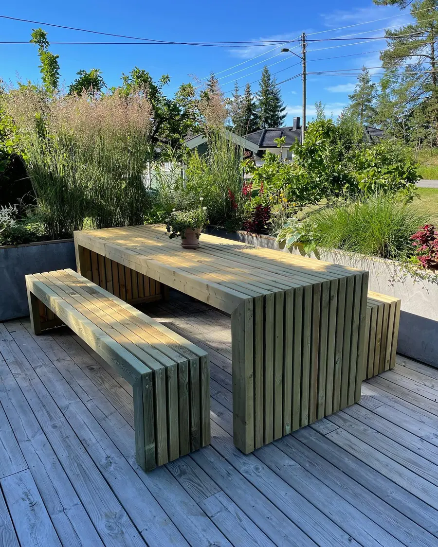 Spesialbygd utebord med matchende benker i tre på en terrasse ved hagen.